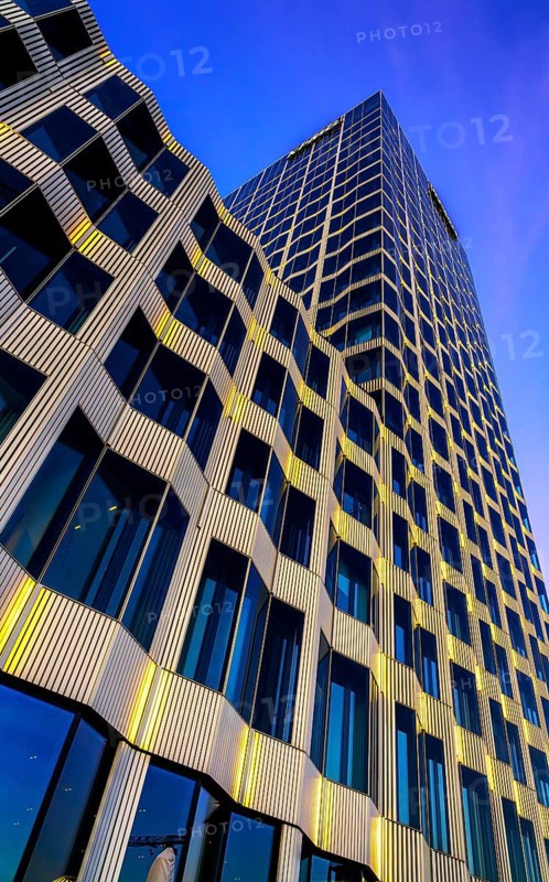 The picture shows a modern office and commercial building at the central station, warm evening light, frog perspective, Berlin, Germany