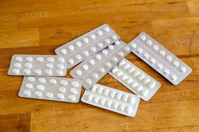 White medical tablets in foil blisters on wooden table top background, UK