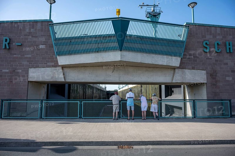 Four people stand in front of a modern lock structure made of concrete and blue railings, Minden waterway junction, Minden-Lübbecke, North Rhine-Westphalia