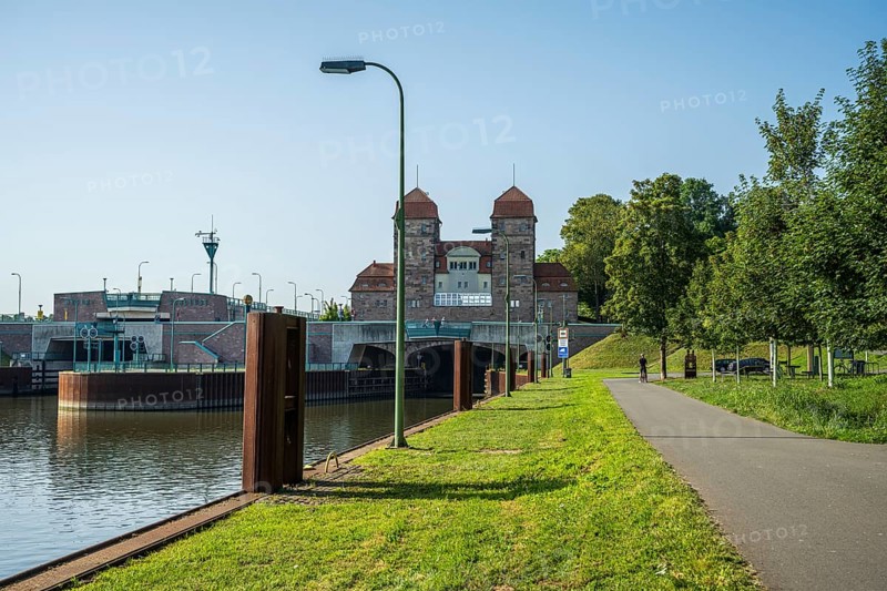 Canal with adjoining lock system and cycle path lined with trees under a blue sky, Minden waterway junction, Minden-Lübbecke, North Rhine-Westphalia