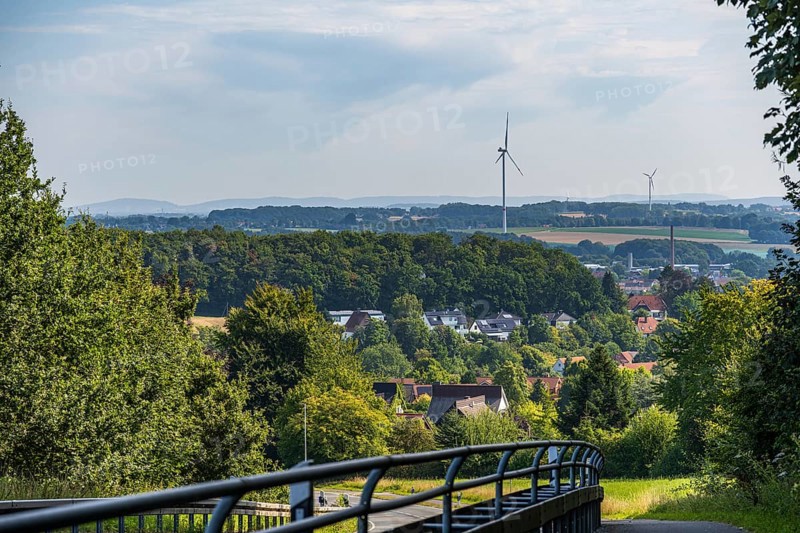 View of a village with wind turbines, surrounded by trees and fields, with a bridge in the foreground, Halle, Werther, Westphalia