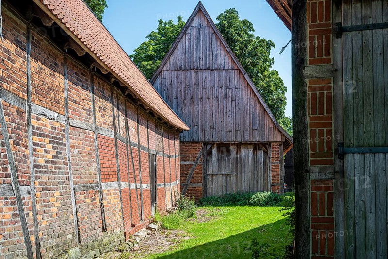 Half-timbered buildings in a green courtyard on a sunny day, Weser cycle path, Schlüsselburg barn quarter, Petershagen, North Rhine-Westphalia