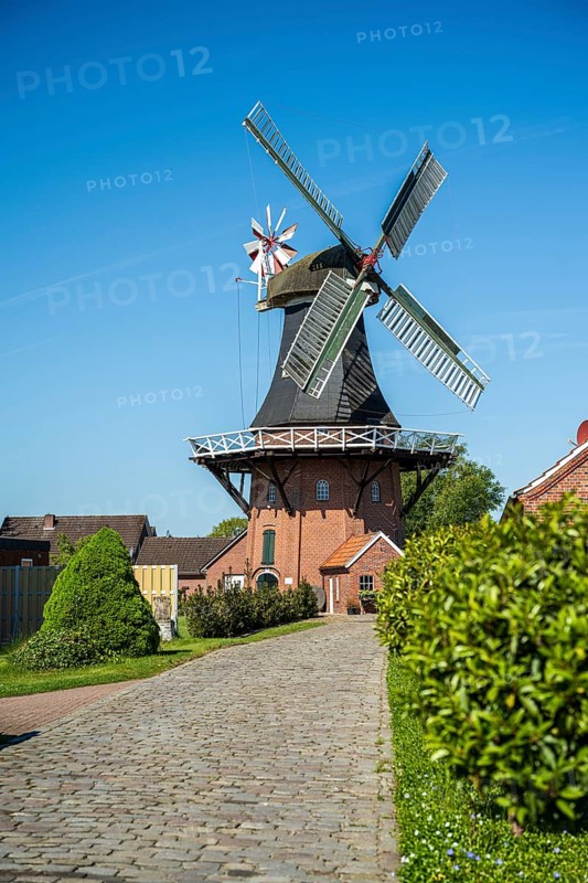 Idyllic windmill near cobbled path and gardens on a sunny day, windmill near Weener