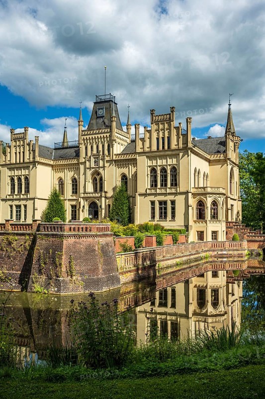 A Gothic castle with moat and towers reflected in the water, Evenburg Castle, Leer, East Frisia