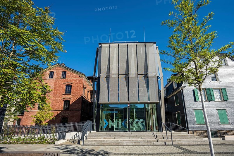 Modern glass building between old houses, surrounded by trees, bright blue sky, Museum of Early Industrialisation in Wuppertal Barmen
