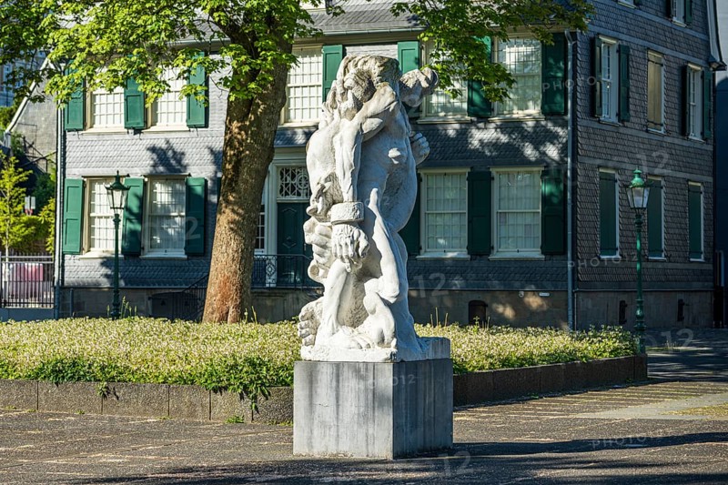 Detailed statue in front of a historic building with clear lines and soft shadows, statue The Strong Left by Alfred Hrdlicka in front of the Friedrich Engels House in Wuppertal Barmen