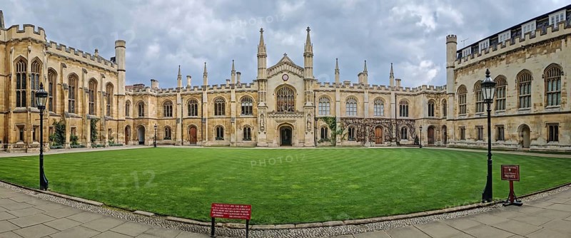 The University of Cambridge panoramic view of a historic college courtyard, featuring a grand, symmetrical facade with Gothic inspired architecture and a central clock tower