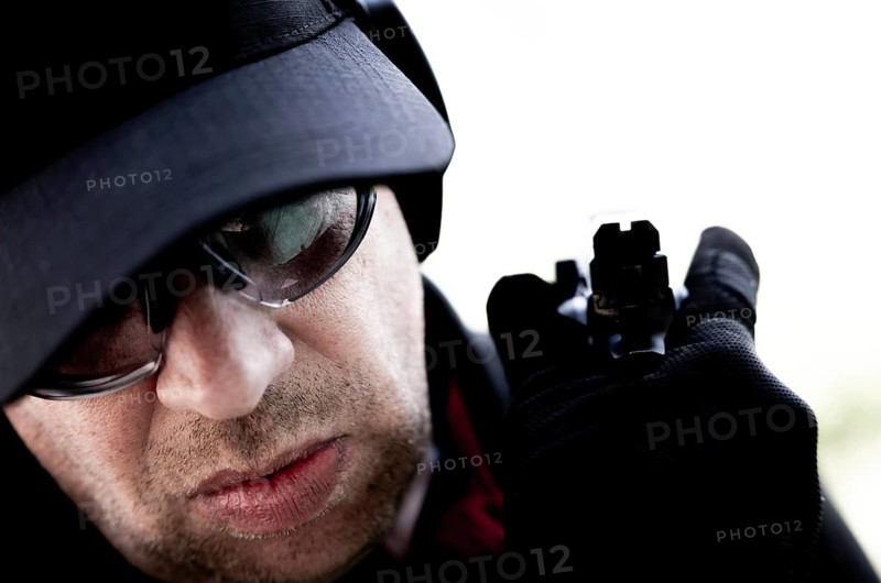 Face of a Man with Cap and Protection Eyeglasses Holding a Handgun Backward in Switzerland