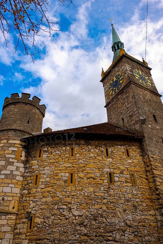 Clock Tower and Fortification Tower and Wall with Blue Sky and Clouds in a Sunny Autumn Day in City of Biel, Bienne, Bern Canton, Switzerland