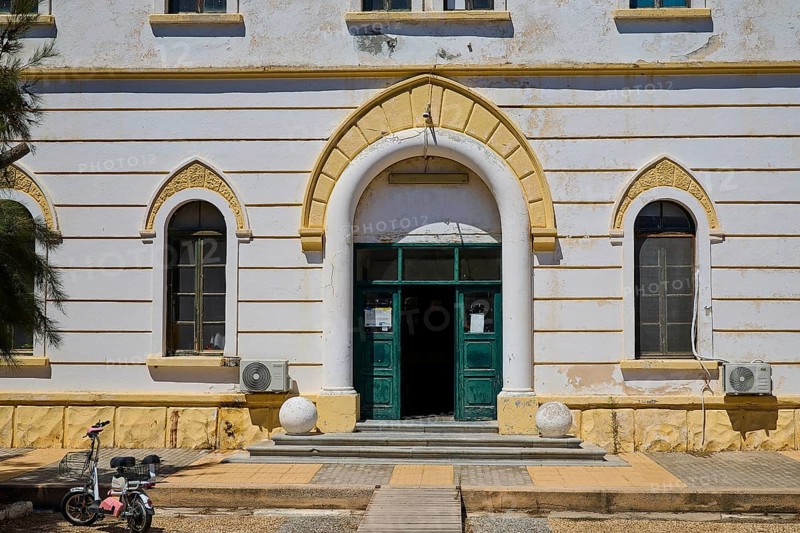 Historic building with arched entrance and small windows, bicycle in front, Historicism, Art Deco, Rationalism, Portolago, Lakki, Leros, Dodecanese, Greek Islands, Greece