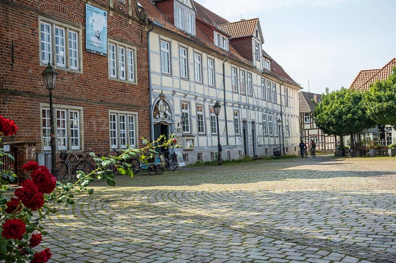 Half-timbered houses with red roses in a cobbled courtyard. Peaceful and historic scenery, Verden an der Aller, Lower Saxony, Germany