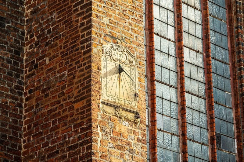 Sundial on a red brick wall next to large Gothic windows, cathedral, Verden an der Aller, Lower Saxony, Germany