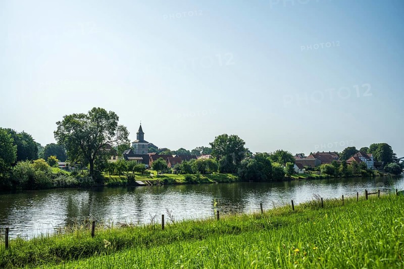 Rural view of a village with a church by the river, surrounded by green nature and a peaceful atmosphere, Weser, St Martin's Church, Hoya, Lower Saxony