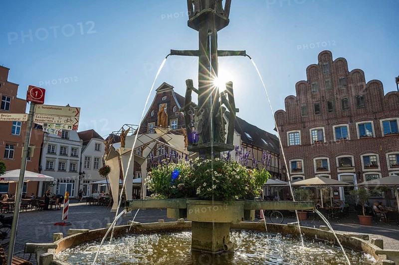 Fountain in the centre of a square surrounded by historic buildings and flowers, Warendorf, Münsterland, North Rhine-Westphalia