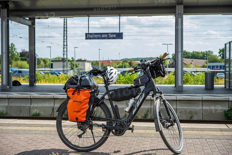 A bicycle with panniers stands at Haltern am See station, surrounded by summery nature and railway tracks, Haltern am See station, Münsterland, North Rhine-Westphalia, Germany