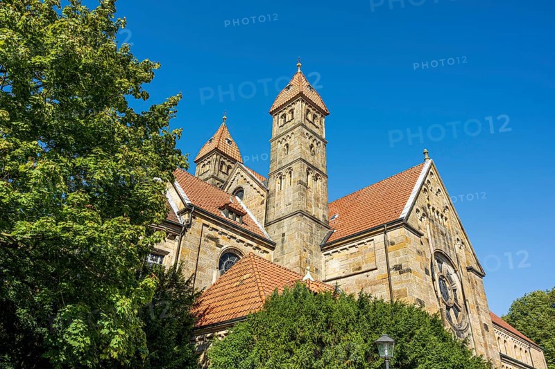 Gothic church with red tiled roofs, surrounded by green trees under a blue sky, St. Mary's Church in Warendorf, Münsterland, North Rhine-Westphalia