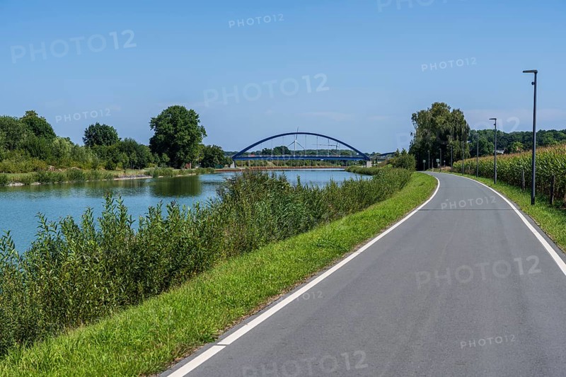 Cycle path along a river with a view of a bridge and green landscape, Dortmund-Ems Canal near Lüdinghausen, Münsterland, North Rhine-Westphalia