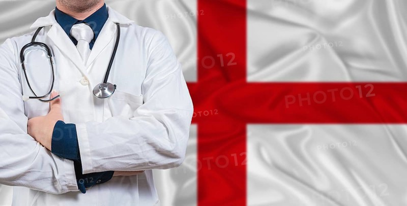 Male doctor with stethoscope on England flag. Doctor holding stethoscope on England flag