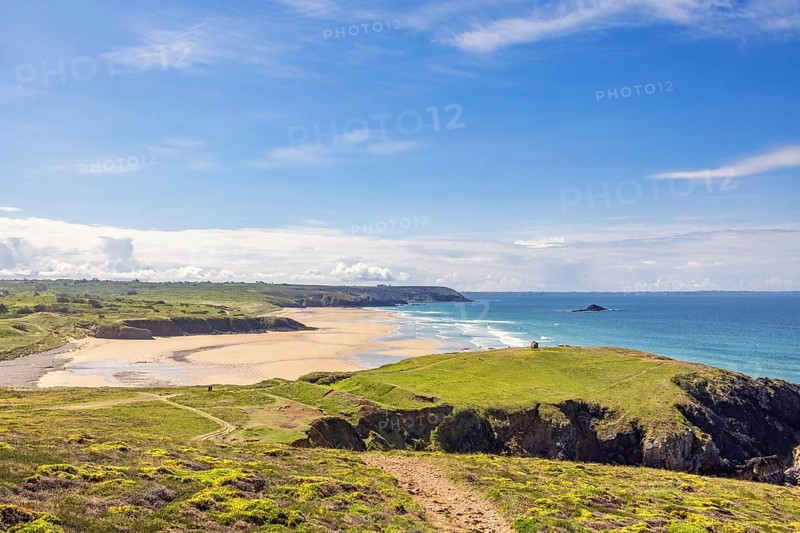 Sunny seascape view in a coastal landscape with a sandy beach and a rocky coastline from a meadow, Crozon peninsula, Bretagne, France