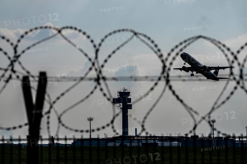 Symbolic image security at the airport, outer fence at Düsseldorf International Airport, steel wire fence, with S-wire rolls, NATO wire, on the top of the fence, aircraft taking off, air traffic control tower, DFS, North Rhine-Westphalia, Germany