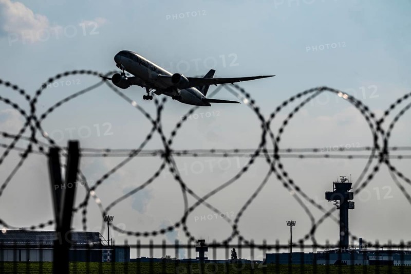Symbolic image security at the airport, outer fence at Düsseldorf International Airport, steel wire fence, with S-wire rolls, NATO wire, on the top of the fence, aircraft taking off, air traffic control tower, DFS, North Rhine-Westphalia, Germany