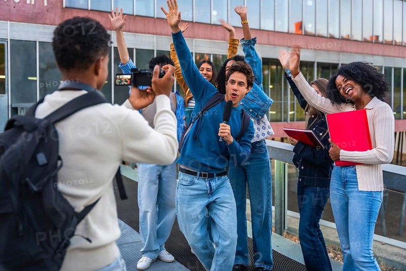 Young diverse students creating social media content together, vlogging on university campus while capturing cheerful moments and expressing happiness