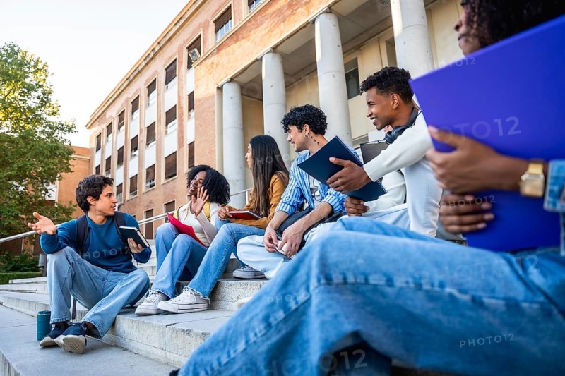 Group of diverse university students sitting on campus steps, discussing and sharing ideas in an educational environment, representing friendship, youth, and multicultural learning