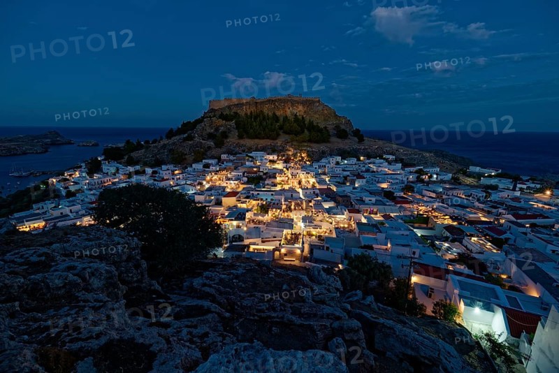 Picturesque Lindos with the ancient Acropolis at dusk with glowing houses and castle in the background, Acropolis, Lindos, Rhodes, Island, Greece