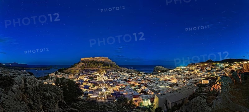 Wide angle photo of the city of Lindos with the ancient Acropolis in a clear night sky with glowing houses, Acropolis, Lindos, Rhodes, Island, Greece