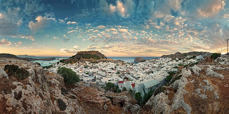 Panoramic view of the Greek town of Lindos by the sea with Acropolis at sunset with dramatic sky and clouds, Acropolis, Lindos, Rhodes, Island, Greece