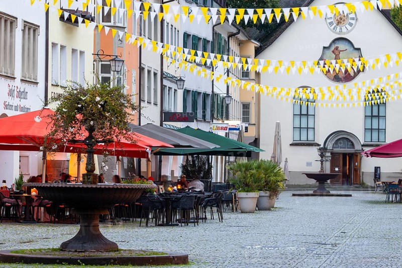 Fountain, outdoor seating at a restaurant, parasols, St John's Church, market square, Feldkirch, Vorarlberg, Austria