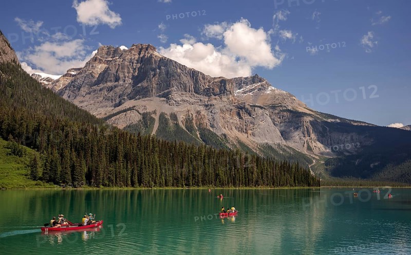 Canoes on Emerald Lake surrounded by forest and the Canadian Rocky Mountains under a clear sky within Yoho National Park in Alberta, Canada, North Canada