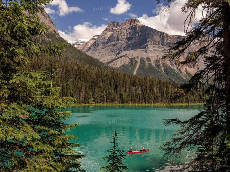 Canoe with explorers on Emerald Lake surrounded by the Canadian Rocky Mountains within Yoho National Park in Alberta, Canada, North Canada