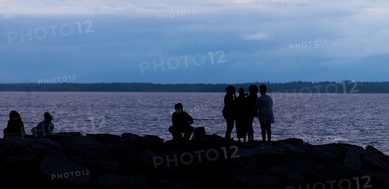 Group of silhouetted figures by a municipal lake at dusk in Ottawa, Ontario, Canada, North America