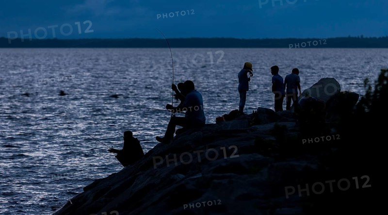 Group of people fishing at night, silhouetted against the water in Ottawa, Ontario, Canada, North America