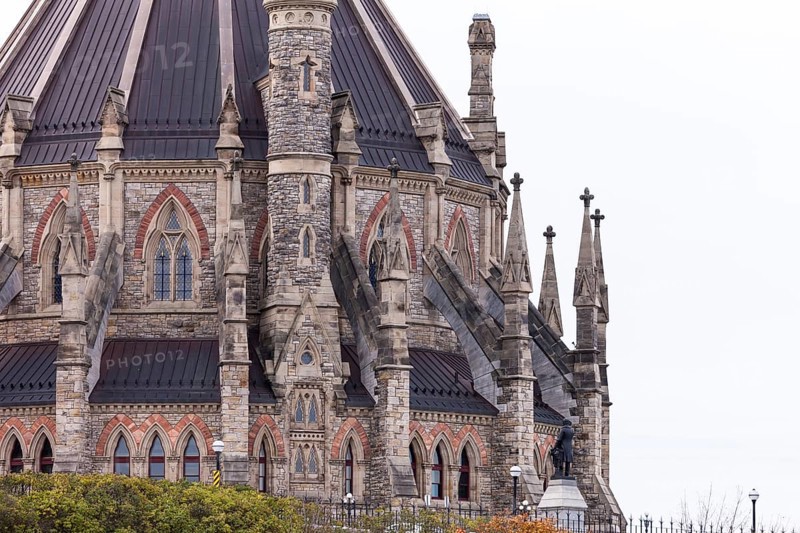 A detailed view of a gothic-style stone building of the Canadian Parliament Buildings with intricate spires in Ottawa, Ontario, Canada, North America