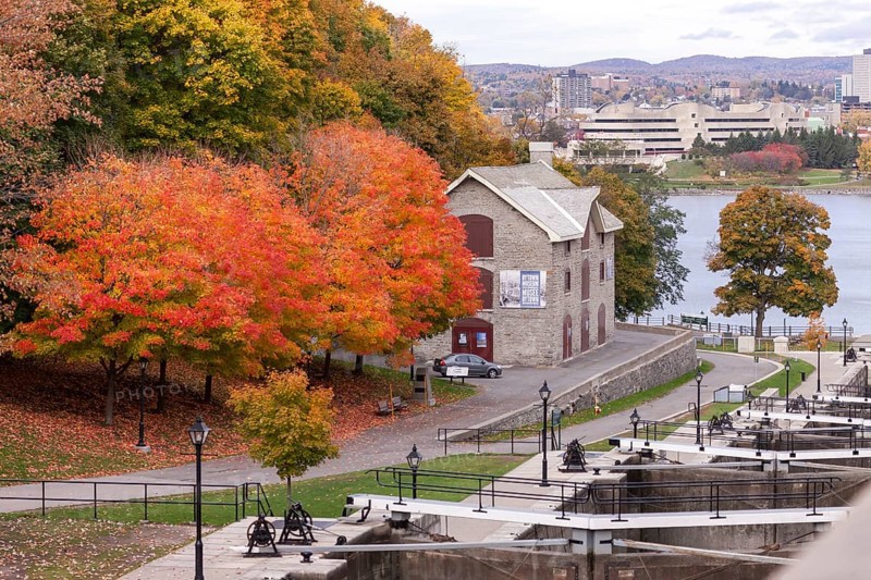 A stone house surrounded by vibrant autumn trees near a river, within a park setting, exuding historical charm in Ottawa, Ontario, Canada, North America