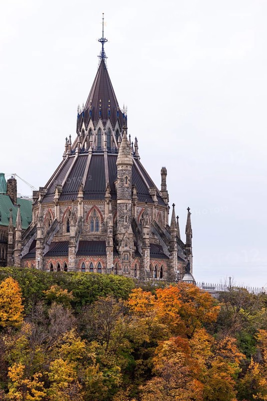 The Canadian Parliament Buildings with spires surrounded by colorful autumn trees in Ottawa, Ontario, Canada, North America