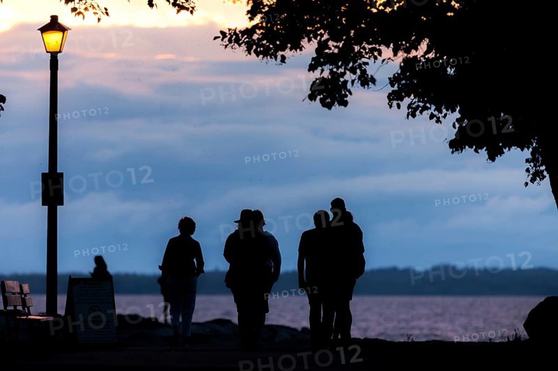 People walking along a tree-lined path at dusk under a streetlamp in Ottawa, Ontario, Canada, North America