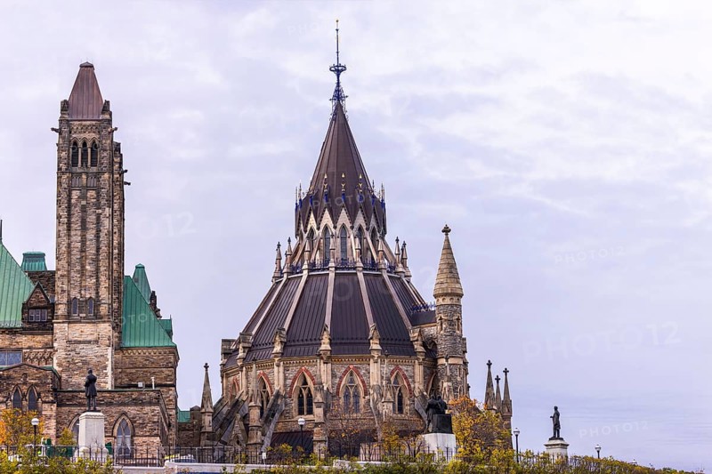 The Canadian Parliament Buildings with an ornate spire and towers against a cloudy sky, showcasing Gothic architectural style in Ottawa, Ontario, Canada, North America