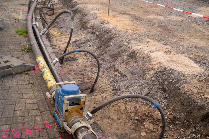Borken, NRW, Germany, Heavy-duty pump and hoses diverting water from an active roadwork excavation