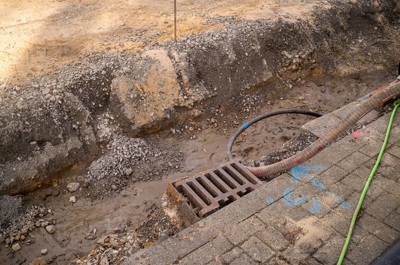 Borken, NRW, Germany, Trench excavation showing earth, mud, gravel, a storm drain, and pipes during roadwork