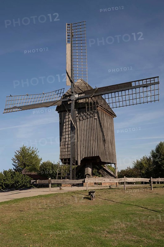 Borken, NRW, Germany, Historic wooden windmill featuring large sails, standing in a green field under a clear blue sky