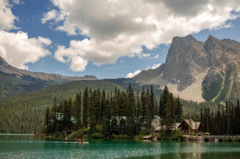 Peaceful Emerald Lake with cabins of Emerald Lake Lodge and forested Canadian Rocky Mountains under a cloud-dotted sky inside Yoho National Park, British Columbia, Canada, North America