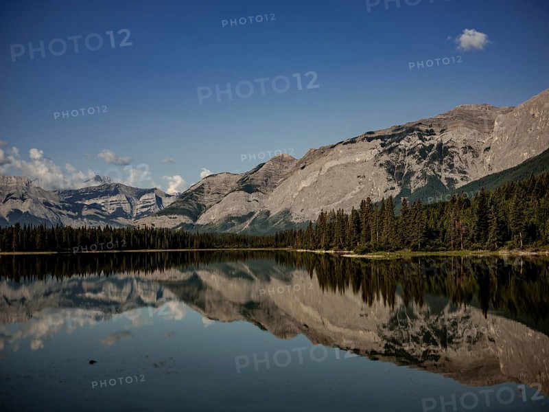 Scenic view of mountains of the Canadian Rocky Mountains mirrored in a still lake on a clear day near Canmore, Alberta, Canada, North America