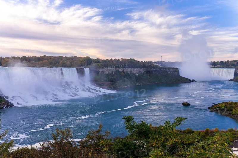 Wide view of the Bridal Veil Falls and the Horseshoe Falls with mist rising under a partly cloudy sky in Niagara Falls, Ontario, Canada, North America