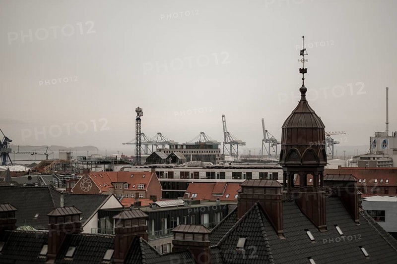 View of a cityscape with rooftops and cranes in the distance under an overcast sky in Aarhus, Denmark, Northern Europe
