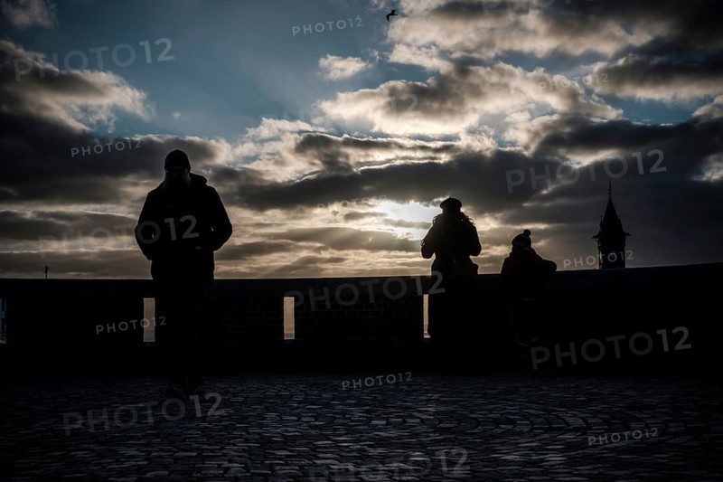 Silhouetted figures at sunset with dramatic clouds and a distant tower in Helsingborg, Sweden, Scandinavia, Northern Europe