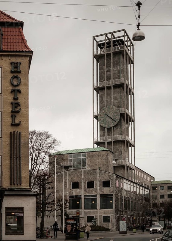A modern concrete building with a large clock under a gray sky in Aarhus, Denmark, Northern Europe