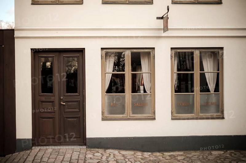 A vintage building facade with wooden doors and windows, featuring cobblestone pavement in Helsingborg, Sweden, Scandinavia, Northern Europe